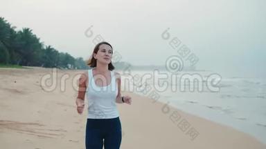 运动女跑步者穿着带表带的智能手表跑，带空白黑色玻璃弯曲触摸屏的天然海洋海滩